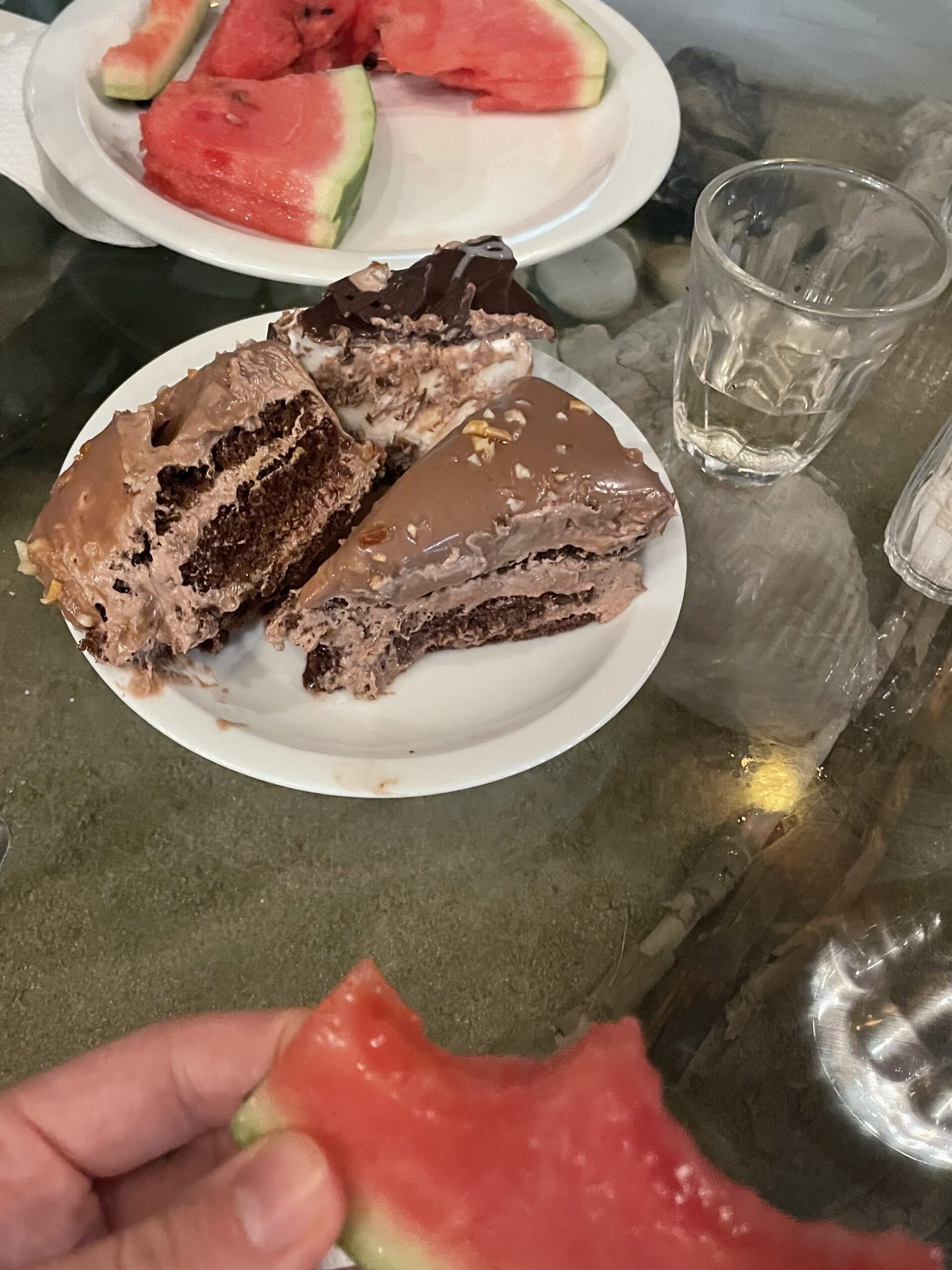 three slices of chocolate cake and watermelon on a plate